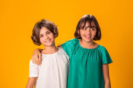 Foto de Retrato de dos hermanas sonrientes sobre fondo amarillo. La edad y la amistad oncept - Imagen libre de derechos