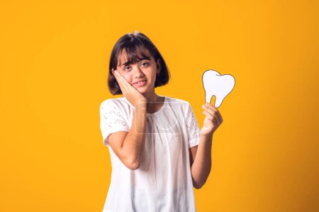 Photo for Child girl holding papercraft tooth and feel toothache. Dental health concept - Royalty Free Image