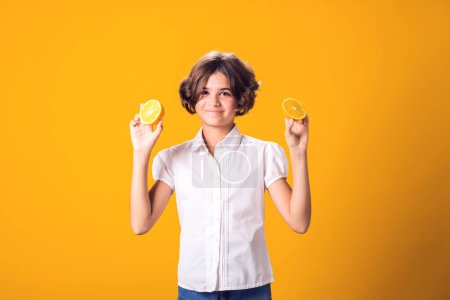 Foto de La chica tiene la mitad de naranja en las manos. Comida saludable, vitaminas y concepto de nutrición para niños - Imagen libre de derechos