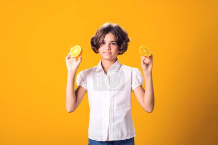 Téléchargez les photos : Fille tient la moitié de l'orange dans les mains. Aliments sains, vitamines et enfants concept nutritionnel - en image libre de droit