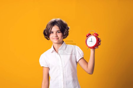 Photo for Child girl holds an alarm clock in hand. The concept of education, school, deadlines, time to study - Royalty Free Image