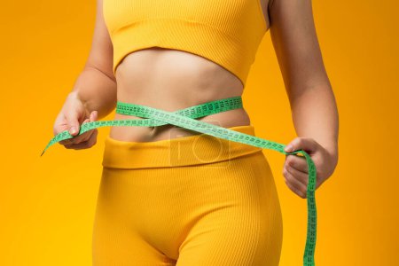 Photo for Fitness woman with measure tape isolated on yellow background. Weight loss and healthcare concept - Royalty Free Image
