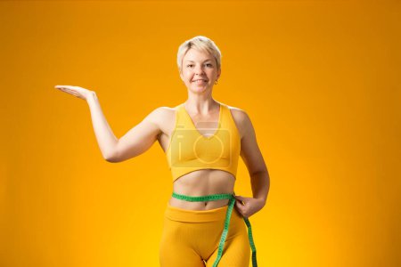 Photo for Fitness woman with short hair with measure tape isolated on yellow background. Weight loss and healthcare concept - Royalty Free Image