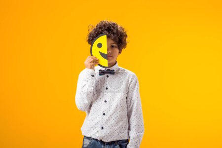 Photo for Upset boy holding happy and sad faces on two pieces of memo paper. emoticon. - Royalty Free Image