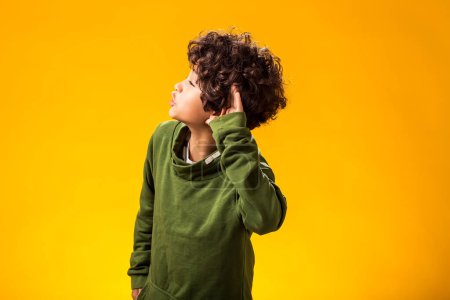 Téléchargez les photos : Portrait d'un enfant écoutant un enfant gardant la main sur son oreille. Concept de confidentialité et de curiosité. - en image libre de droit