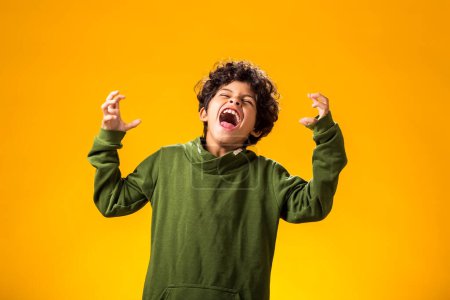 Foto de Retrato de niño enojado sobre fondo amarillo. Concepto de emociones negativas para niños - Imagen libre de derechos