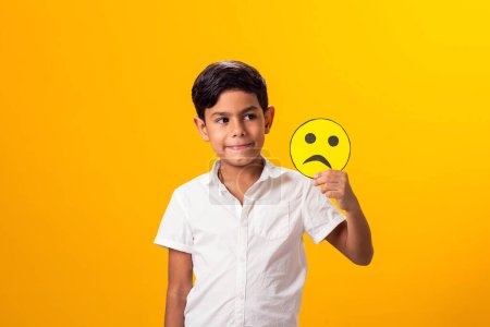 Foto de Niño feliz sosteniendo emoticonos de papel buen y mal humor - Imagen libre de derechos