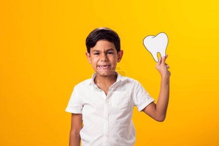 Foto de Muchacho sosteniendo un diente de papel. Concepto de salud dental - Imagen libre de derechos
