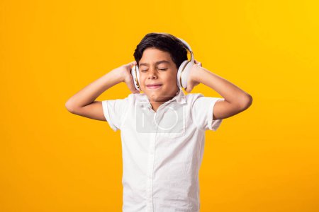 Téléchargez les photos : Portrait d'un gamin avec casque écoutant une musique. Concept de loisirs et de divertissement - en image libre de droit