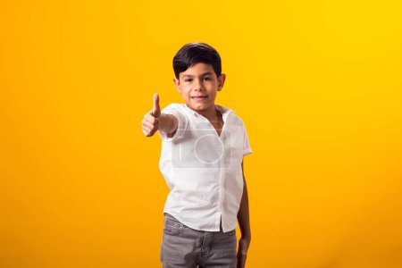 Photo for Portrait of kid boy showing thumb up gesture over yellow background. - Royalty Free Image