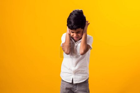 Photo for Portrait of kid boy covering ears over yellow background. Noise, stress and childhood concept - Royalty Free Image