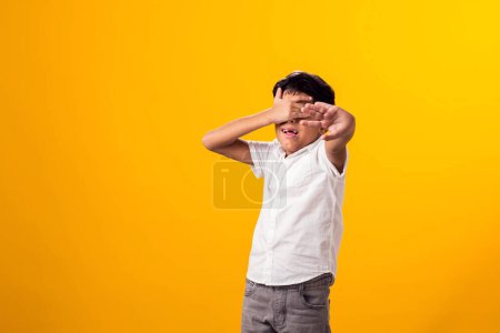 Photo for Portrait of scared kid boy showing stop gesure and covering eyes over yellow background.Violence and depression concept - Royalty Free Image