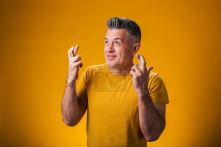Téléchargez les photos : Portrait d'homme montrant le geste des doigts croisés, anticiper l'audition de bonnes nouvelles. Concept d'excitation - en image libre de droit