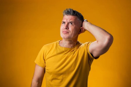Photo for Portrait of man confuse and wondering about question. Thinking with hand on head over yellow background. Pensive concept. - Royalty Free Image