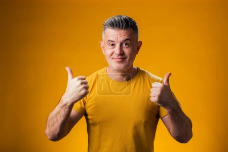 Photo for Portrait of man showing thumb up gesture over yellow background. People and emotion concept - Royalty Free Image