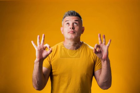 Photo for Portrait of man meditating, keeping calm, over yellow background. Relaxation concept - Royalty Free Image