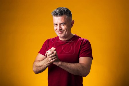 Photo for Portrait of smiling man rubbing hands over yellow background. Success and optimistic concept - Royalty Free Image