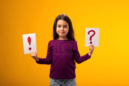 Photo for A portrait of smiling kid girl holding cards with question mark and exclamation point. Children, idea and knowledge concept - Royalty Free Image