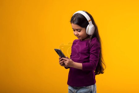 Photo for Portrait of smiling girl enjoying music in headphones on yellow background. Lifestyle, leasure and gadget addiction concept - Royalty Free Image
