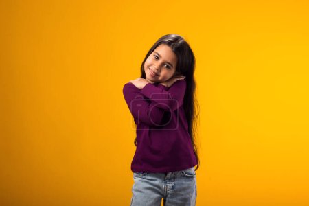 Photo for Portrait of child girl standing over isolated yellow background hugging oneself happy and positive, smiling confident. Self love and self care - Royalty Free Image