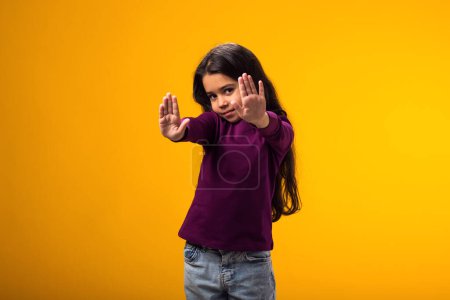 Porträt eines Mädchens mit Stop-Geste auf gelbem Hintergrund. Bulling und negative Emotionen