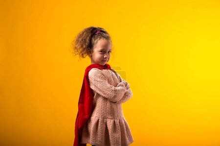 Foto de Portait de niña superhéroe con una capa roja sobre fondo amarillo. Concepto de victoria y éxito. - Imagen libre de derechos