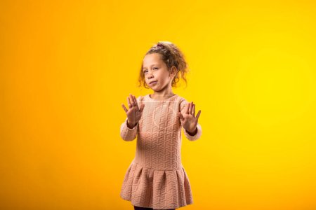 Foto de Retrato de niña mostrando gesto de stop sobre fondo amarillo. Concepto de bulling y emociones negativas - Imagen libre de derechos
