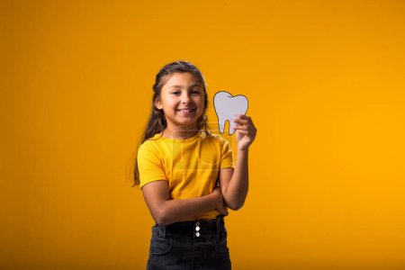 Téléchargez les photos : Enfant souriant tenant une dent de papercraft. Concept de santé dentaire - en image libre de droit