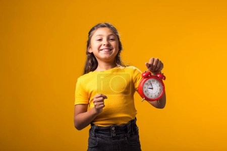 Photo for Portrait of smiling kid girl holding an alarm clock in hand. The concept of education, school, deadlines, time to study - Royalty Free Image