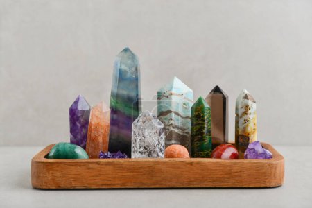 Minerals towers of Fluorite, Smoky Quartz, Amethyst, Crackle Quartz, Aragonite, Amazonite, Emerald, Fire Quartz in wooden tray  on light background