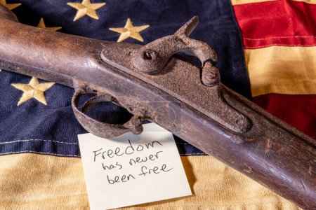 Photo for Old musket gun on American flag with freedom has never been free note - Royalty Free Image
