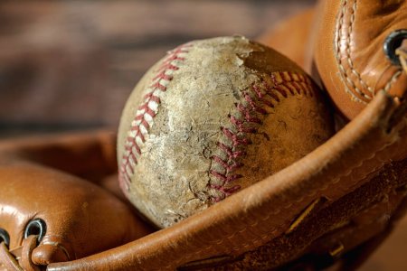 Foto de Cerrar el viejo béisbol desgastado aislado en guante de béisbol de cuero - Imagen libre de derechos