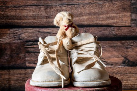 Foto de Vintage 67 años de edad zapatos de bebé de cuero blanco con pequeño oso de peluche y cordones originales - Imagen libre de derechos