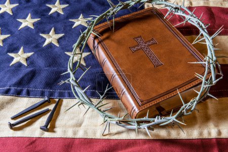 leather bible and crown of thorns on American flag with old rose head nails