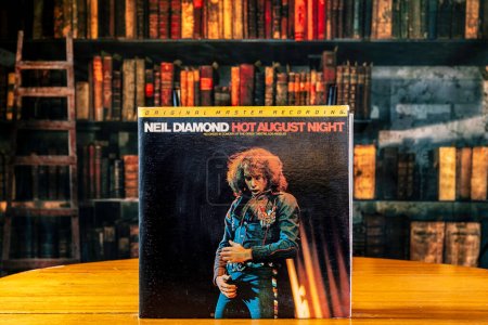 Photo for Chambersburg, Pennsylvania, USA, 06-06-2023 vintage Neil Diamond vinyl record Hot August Night on table with retro looking library background - Royalty Free Image
