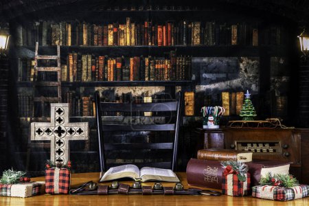 Foto de Motivo de la temporada Decoraciones navideñas sobre mesa con cruz y biblia con fondo antiguo de biblioteca - Imagen libre de derechos