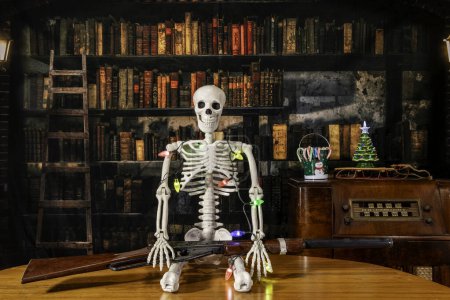 Foto de Esqueleto envuelto en luces de Navidad con pistola retro bb con radio vintage y fondo de biblioteca antigua - Imagen libre de derechos