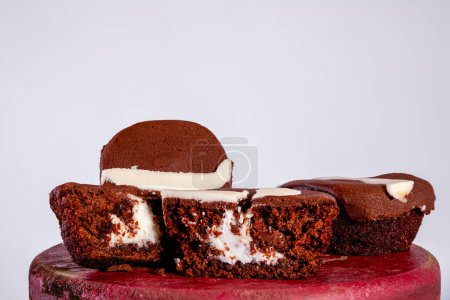 Foto de Three chocolate cupcakes on cut in half showing cream filling isolated on white background - Imagen libre de derechos