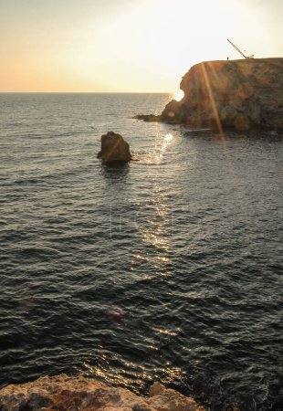 Foto de Crimea, Atlesh, silhouette of a crane fishermen on a cape in the rays of the setting sun - Imagen libre de derechos
