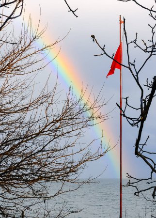 Photo for Red flag on the background of a multi-colored rainbow over the sea, the Black Sea - Royalty Free Image