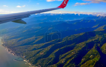 Téléchargez les photos : TRABZON, Turkiye - 22 OCTOBRE 2014 : Vue de l'aile de l'avion et de la ville côtière et des maisons des Turcs éparpillées sur les montagnes vertes depuis la fenêtre de l'avion en Turquie - en image libre de droit
