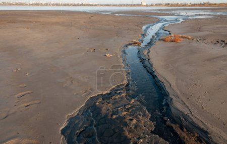 Photo for Salt water with black mud flows from the Kuyalnik sanatorium to the Kuyalnik estuary - Royalty Free Image