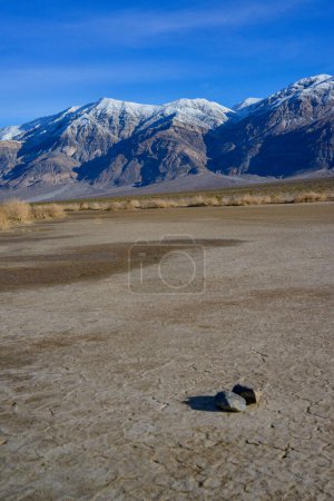 Photo for Landscape of wet clay desert in winter against the backdrop of snow-capped mountains in the Death Valley area, California - Royalty Free Image