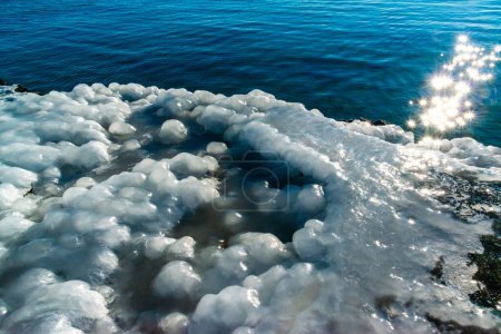 Vereisung eines Betonpfeilers im Schwarzen Meer, Eisblöcke glitzern in der Sonne, Eis am Meer, Odessa
