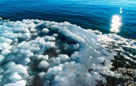 Icing of a concrete pier in the Black Sea, blocks of melted ice glisten in the sun, ice by the sea, Odessa