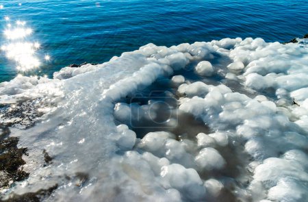Vereisung eines Betonpfeilers im Schwarzen Meer, Eisblöcke glitzern in der Sonne, Eis am Meer, Odessa