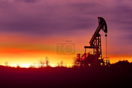 Ölpumpen bei Sonnenuntergang, Industrieölpumpen Ausrüstung. Sonnenuntergang und Dunkelheit. Ölfeld im Nebel. Rot getöntes abstraktes Bild. Krise in der Ölindustrie.