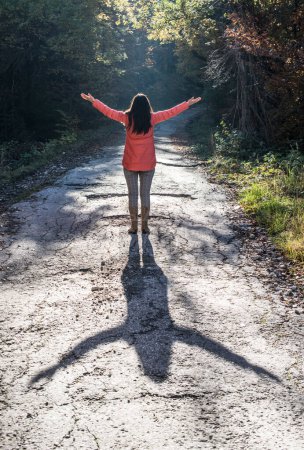 Téléchargez les photos : Femme dans la forêt les mains tendues contre le soleil - en image libre de droit