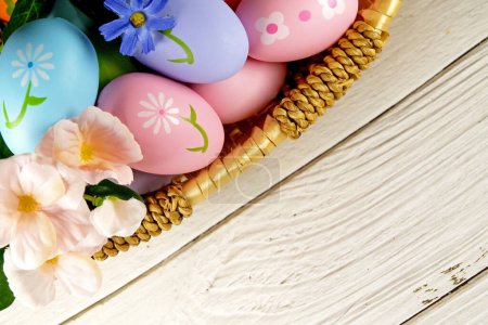Foto de Huevos de Pascua y flores en cesta sobre fondo blanco. concepto de Pascua. espacio de copia - Imagen libre de derechos