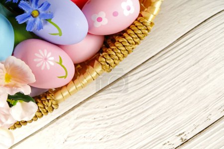 Foto de Huevos de Pascua y flores en cesta sobre fondo blanco. concepto de Pascua. espacio de copia - Imagen libre de derechos